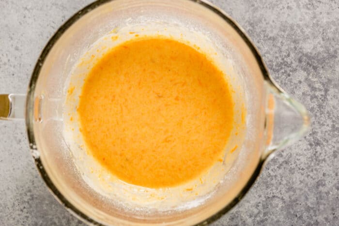 orange-hued batter in a large glass mixing bowl