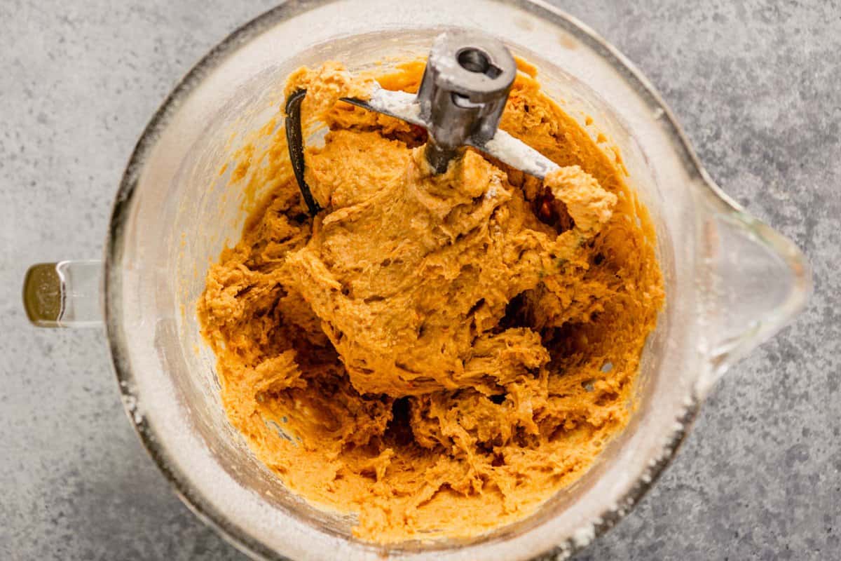 orange-hued dough in a large glass mixing bowl