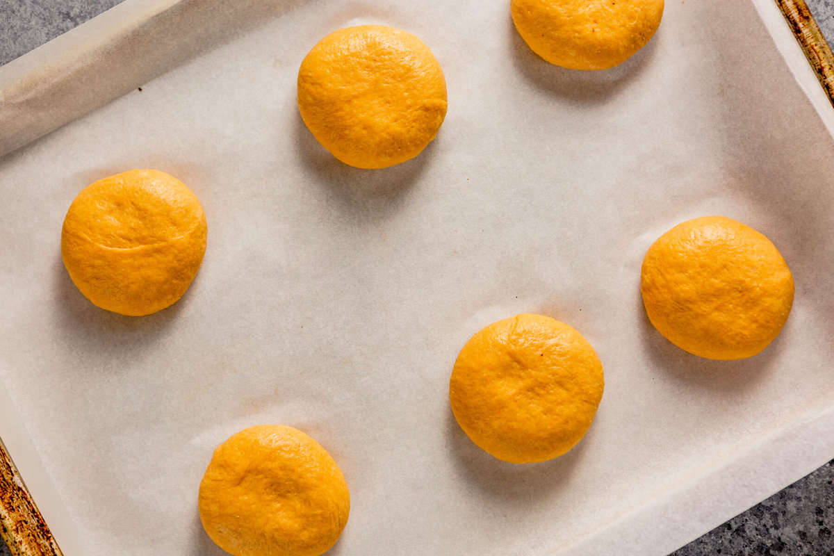 orange-hued dough balls arranged on a parchment-lined baking sheet