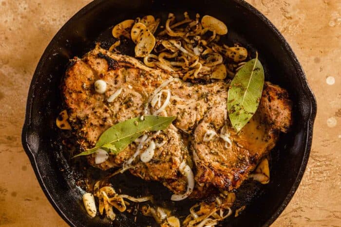cooked pork in a cast-iron skillet with onions and garlic