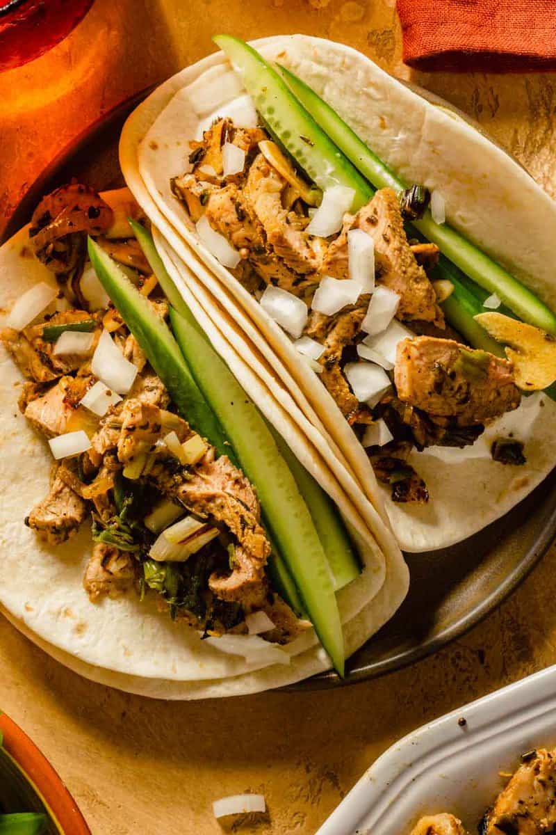 pork tacos topped with cucumber and raw onion