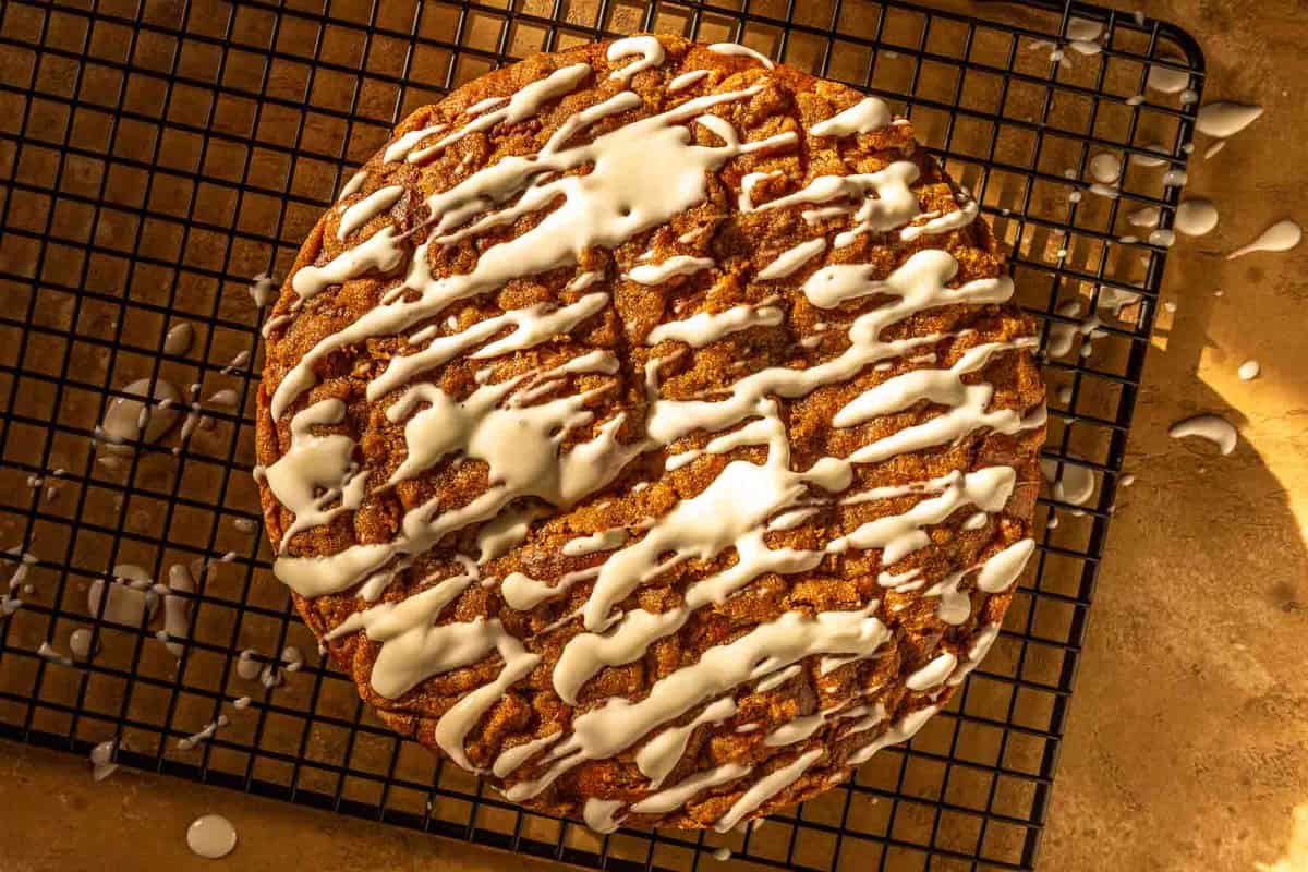 coffee cake on a black wire rack with a cream cheese drizzle on top