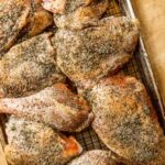 raw turkey pieces covered in salt and spices on a baking sheet