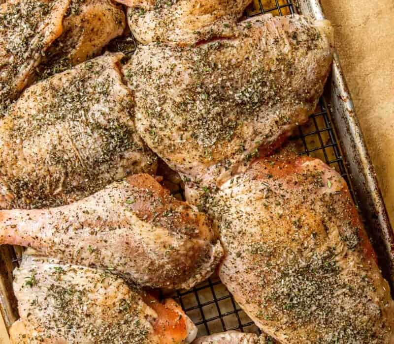 raw turkey pieces covered in salt and spices on a baking sheet