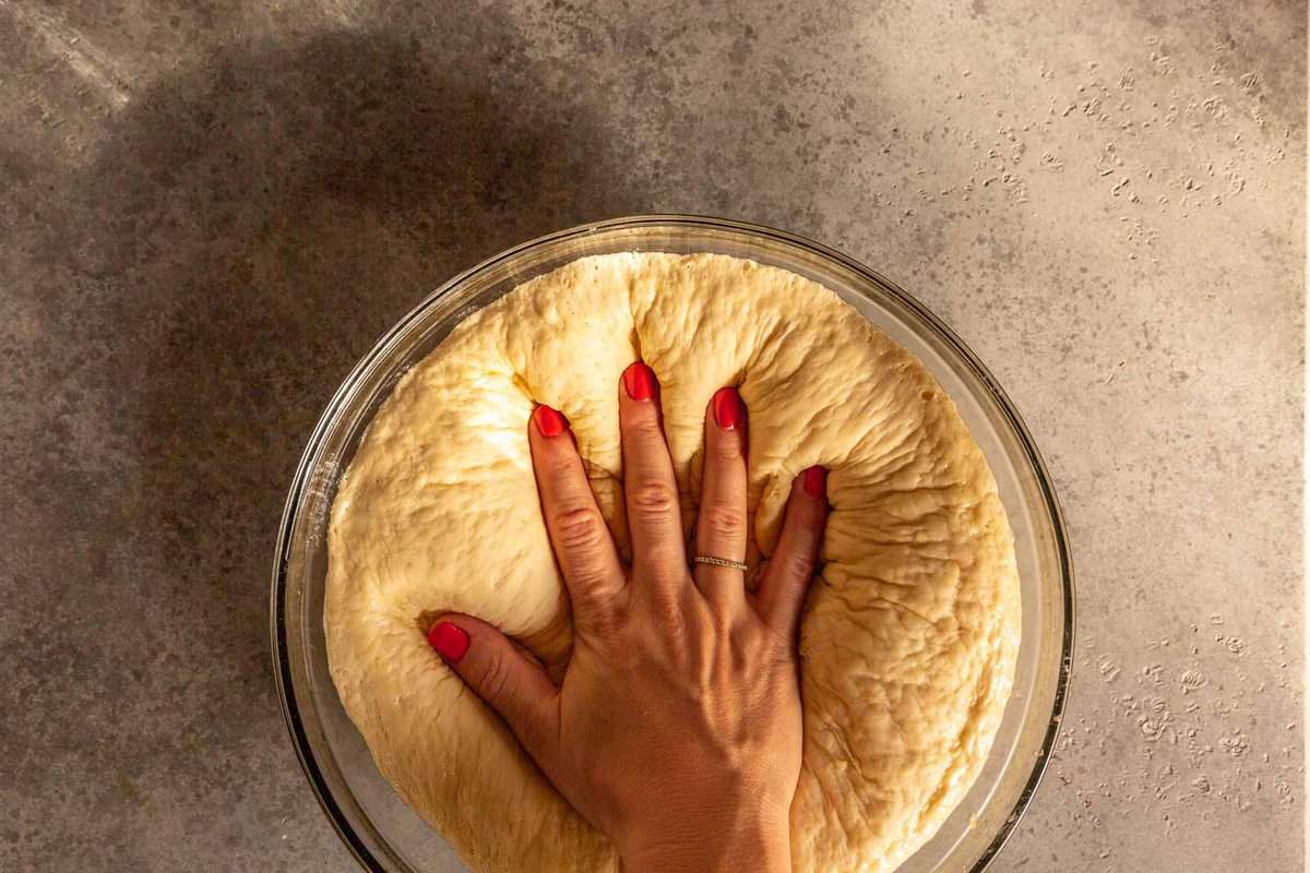 a hand pressing dough risen bread dough