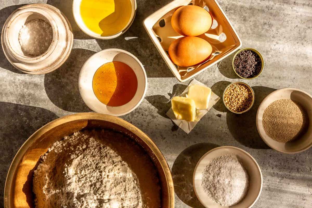 flour, eggs, honey, butter, spices, yeast and oil arranged on a counter top