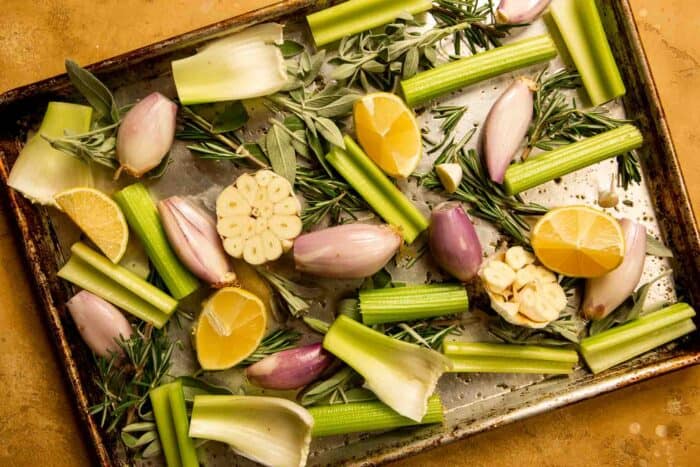 celery, shallots, lemon, herbs, and garlic on a baking sheet