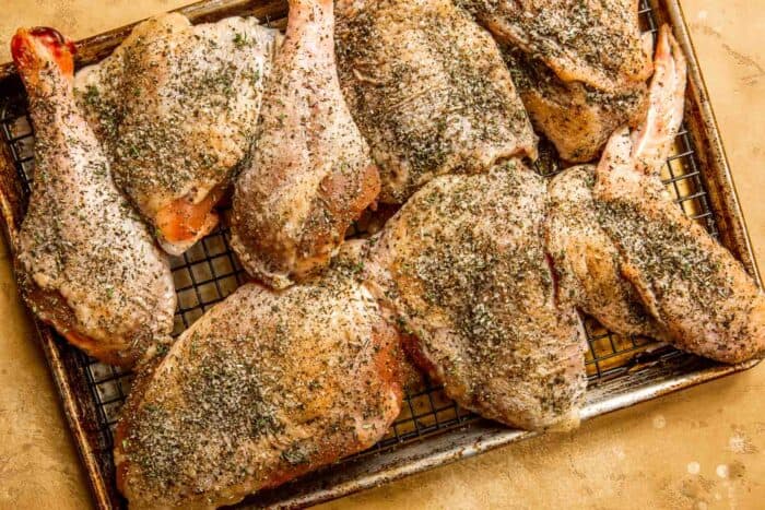 raw turkey pieces covered in salt and spices on a baking sheet