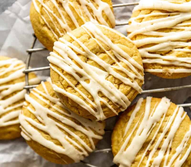 yellow-hued snickerdoodle cookies with glaze set on a wire rack