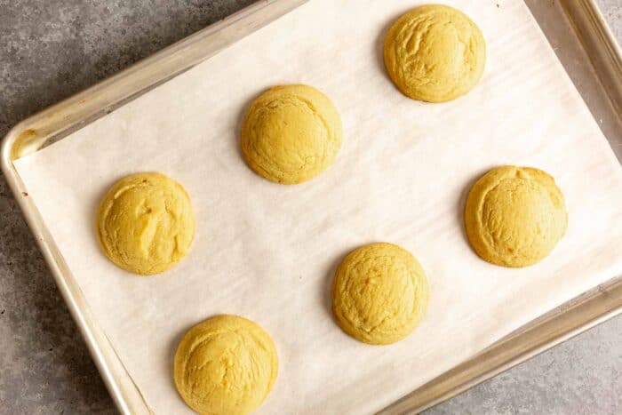 yellow-hued cookies on a parchment lined baking sheet