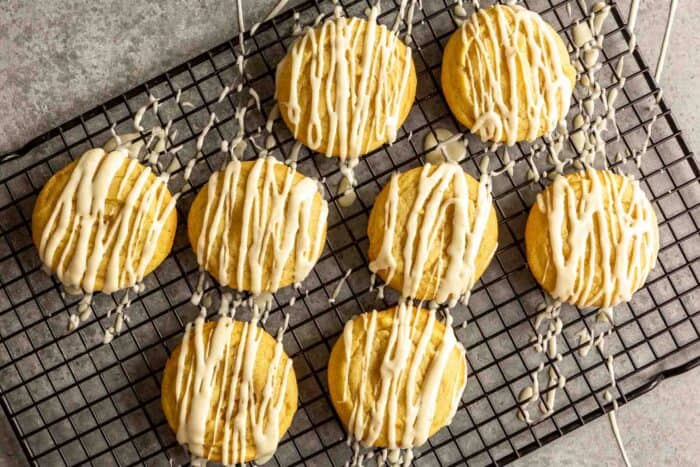 yellow-hued snickerdoodle cookies with glaze set on a wire rack
