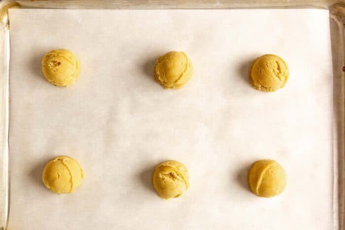 scoops of cookie dough on a parchment lined baking sheet