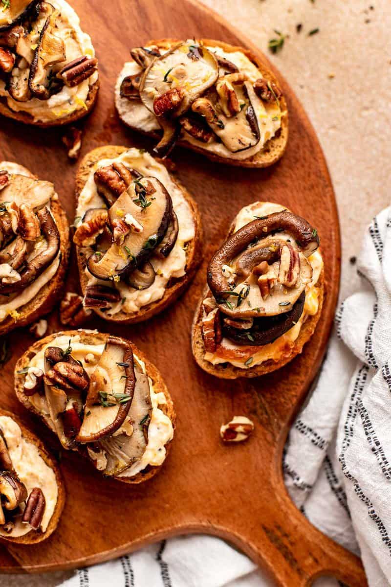 crostini topped with cheese and mushrooms on a wood boardv