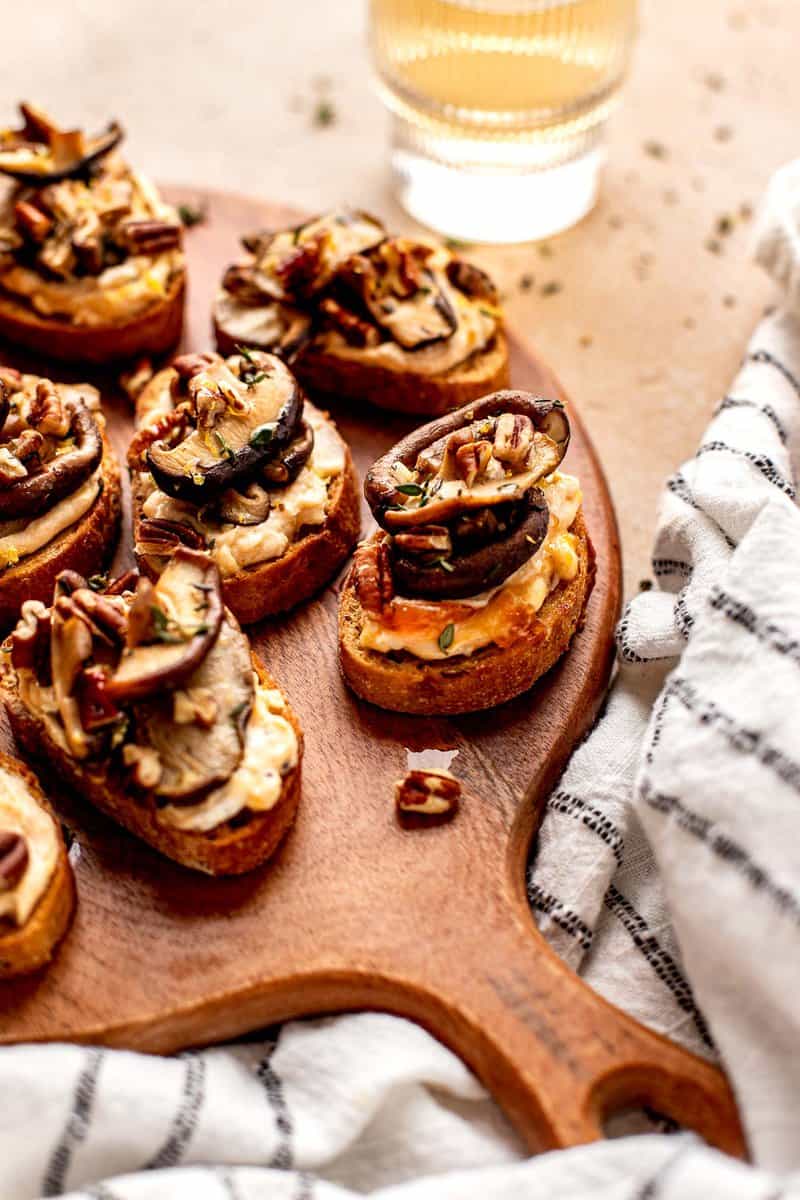 crostini topped with cheese and mushrooms on a wood board