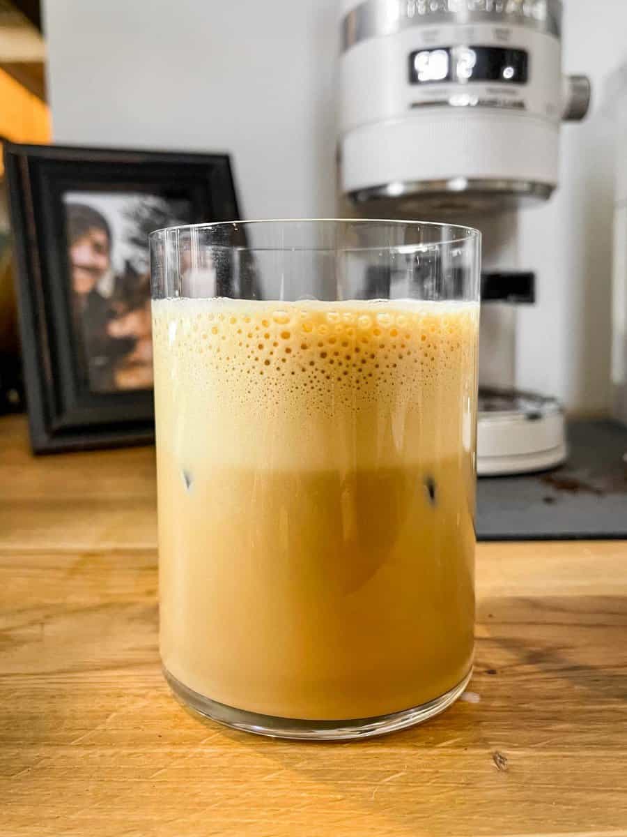 iced latte in a tall glass on a wood countertop