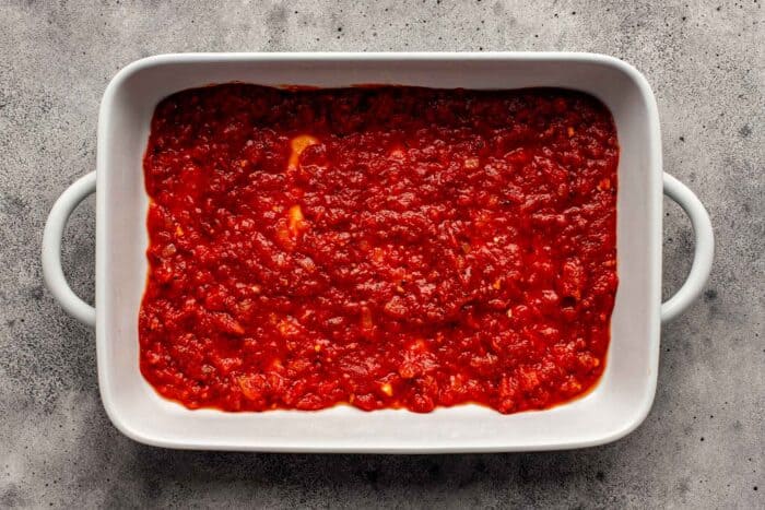 tomato sauce spread into the bottom of a baking dish