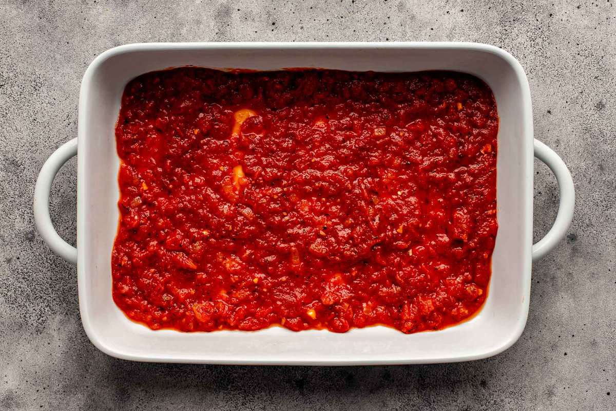 tomato sauce spread into the bottom of a baking dish