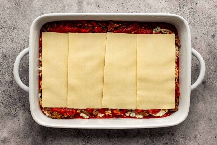 lasagna sheets layered in a large white baking dish