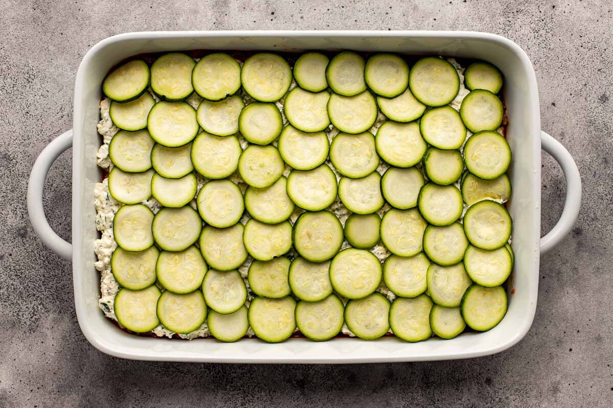 zucchini slices layered in a large white baking dish