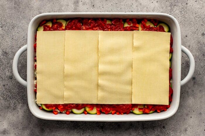 lasagna sheets layered in a large white baking dish
