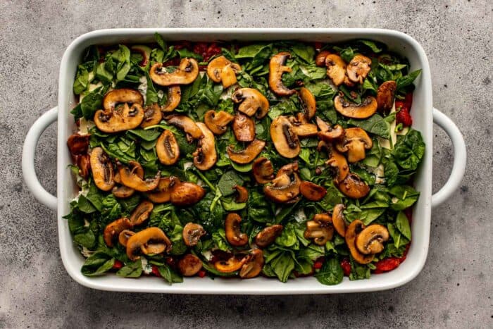 spinach and mushrooms layered in a large white baking dish