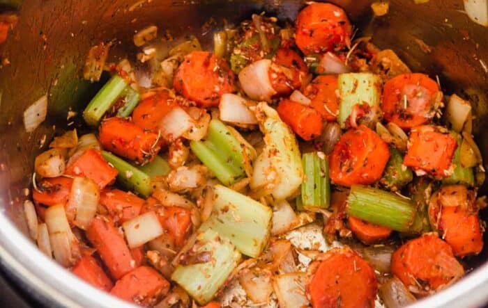 chunks of carrots, onions and celery seasoned with tomato paste and garlic in an instant pot