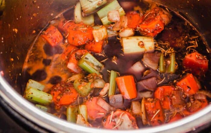 chunks of carrots, onions and celery simmering in red wine in an instant pot