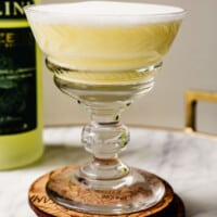 yellow-hued cocktail in a martini glass set on wood coasters