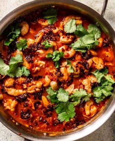 fresh cilantro, chili crisp, and shrimp in a spicy tomato sauce in a sauté pan