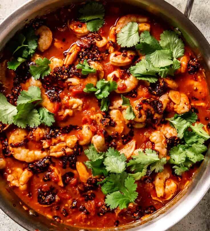 fresh cilantro, chili crisp, and shrimp in a spicy tomato sauce in a sauté pan