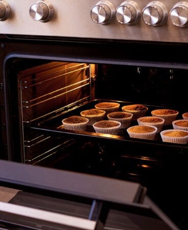 oven with door open showing cupcakes baking