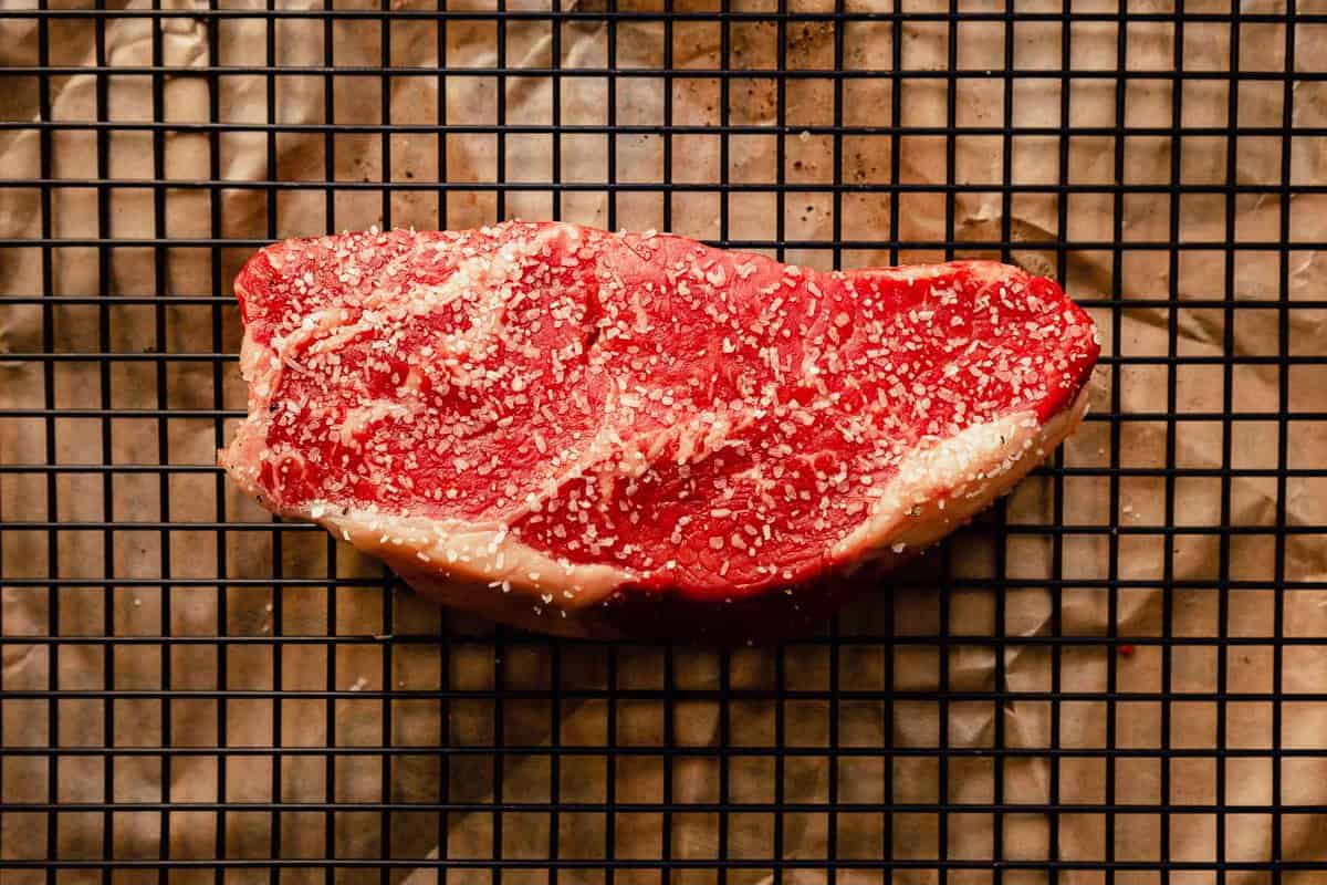 a large new york stip steaks seasoned with salt and set on a wire rack