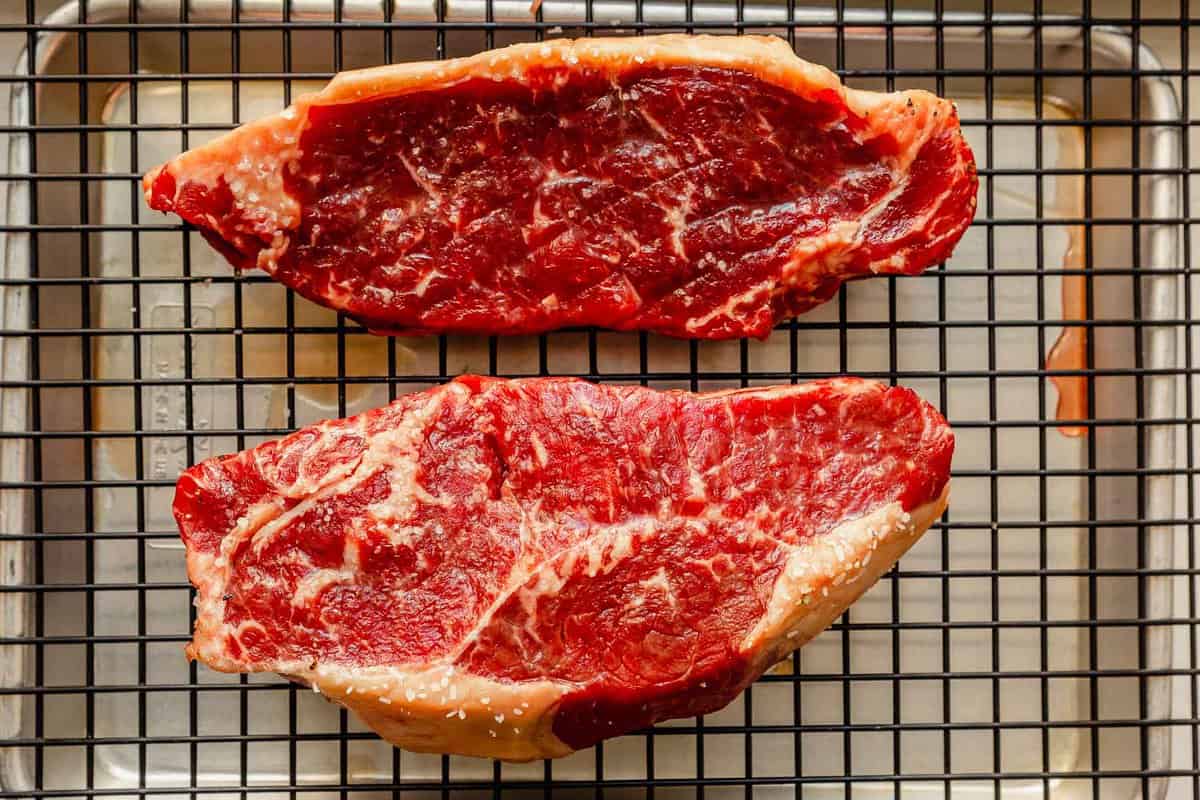 two large new york stip steaks seasoned with salt and set on a wire rack