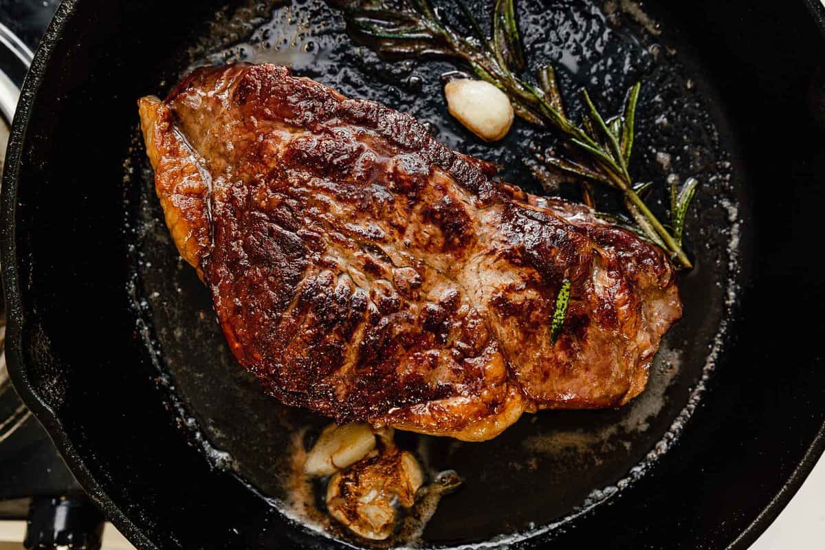 large steak searing in a cast-iron skillet