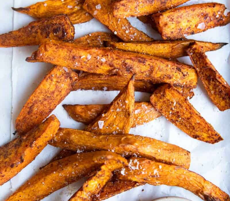 sweet potato wedges on a white platter with a side of dipping sauce