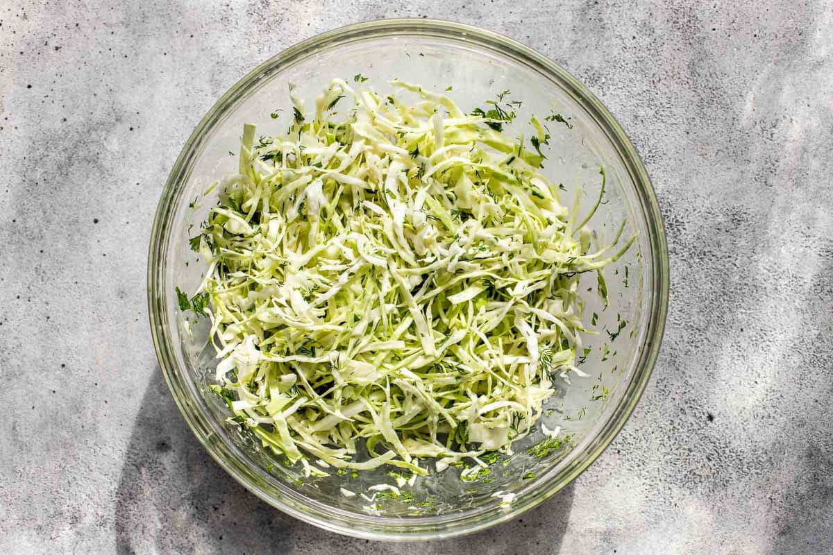 shredded cabbage and herbs in a large glass bowl