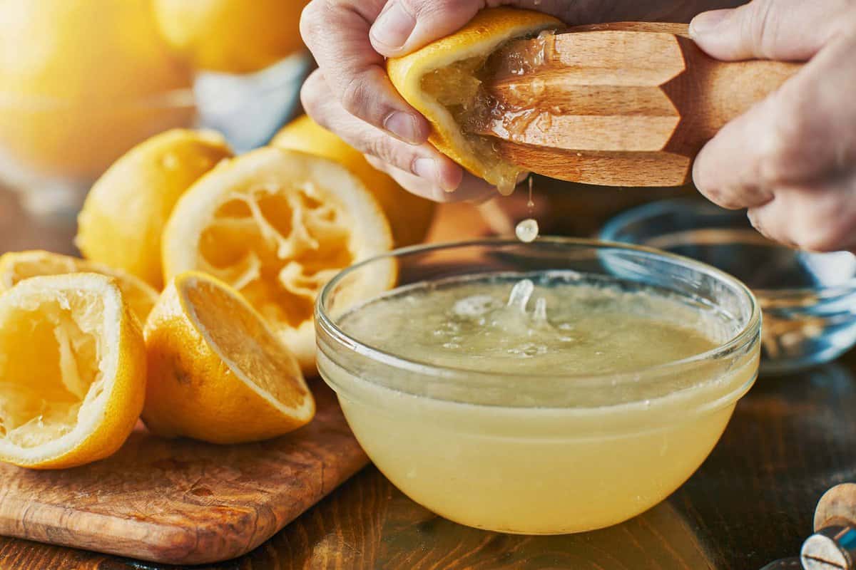 fresh lemon juice getting squeezed into a glass bowl