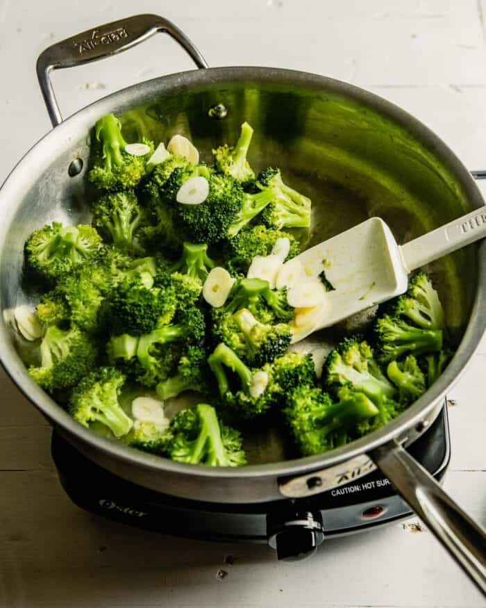 broccoli and sliced garlic cooking in a saute pan