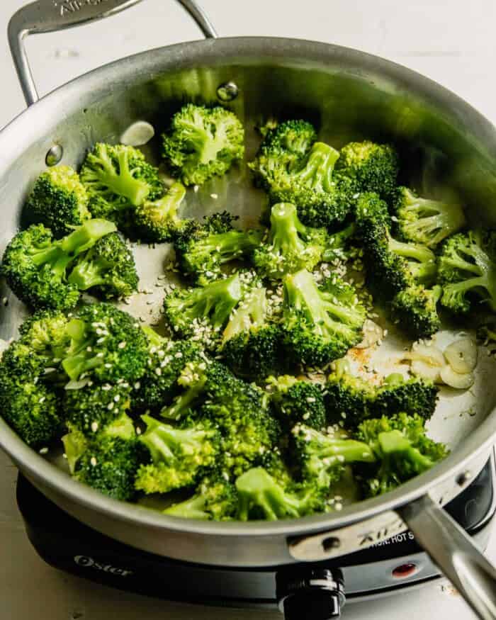 broccoli and sliced garlic cooking in a saute pan