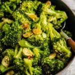 sautéed broccoli in a shallow blue bowl with a wooden-handled spoon