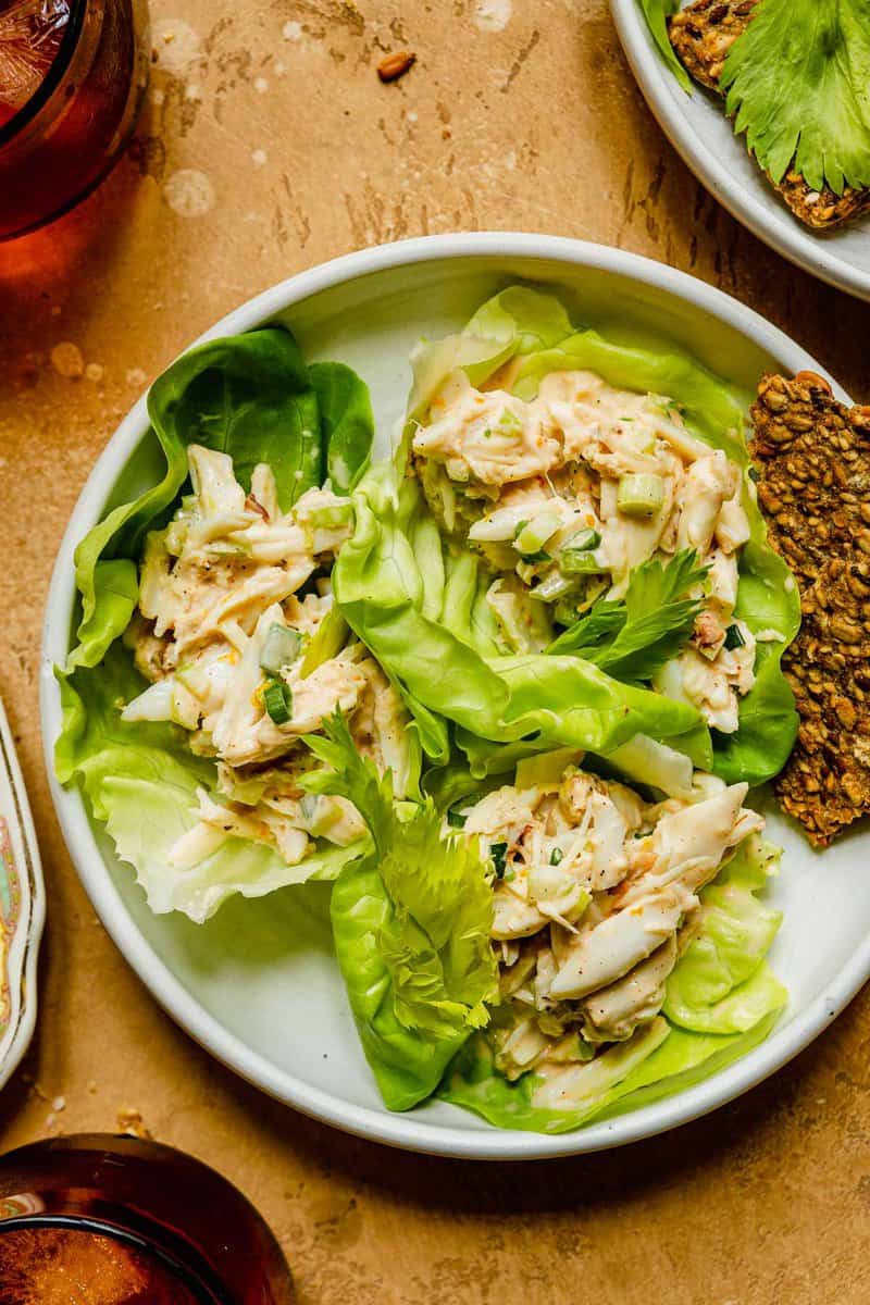 three lettuce wraps in a shallow white bowl. lettuce wraps filled with creamy crab salad