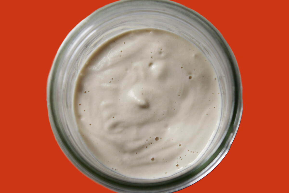 cashew cream in a jar set on an orange background