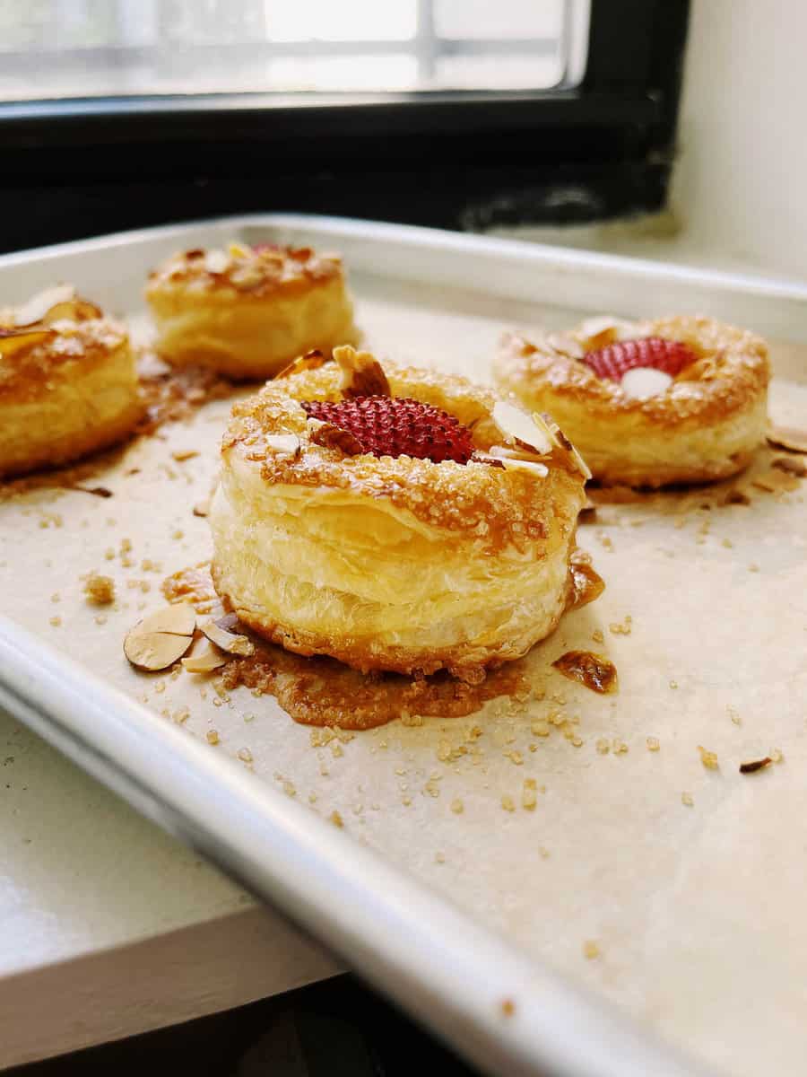 round puff pastries topped with sugar, almonds and a roasted strawberry