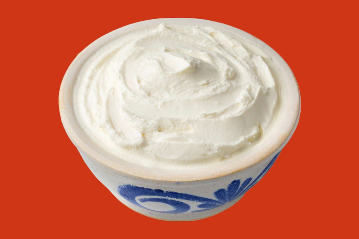 fromage blanc spread into a white and bowl set against an orange background