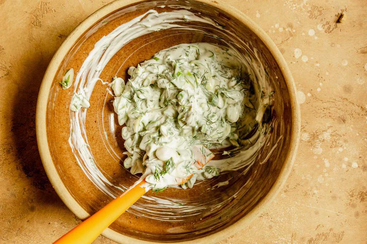creamy herb dressing in a brown bowl with a spatual