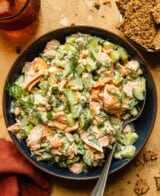 chunks of salmon and cucumber in a dark blue bowl with a spoon set in it