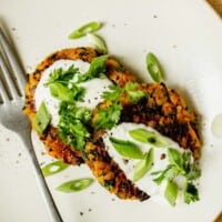 vegetable croquettes on a white plate topped with greek yogurt and fresh herbs