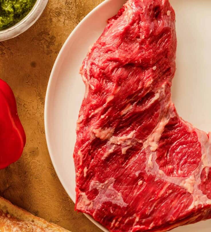 raw tri tip steak on a small white plate