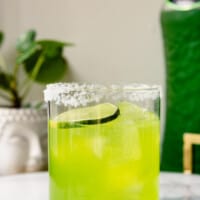 Vibrant green cocktail in a rocks glass rimmed wit salt and garnished with a lime wheel
