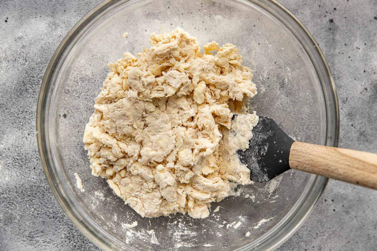 chunks of butter cut into flour in a glass mixing bowl.